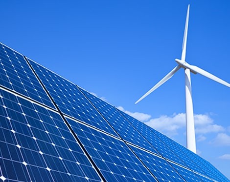 Solar panels and wind turbine against blue sky