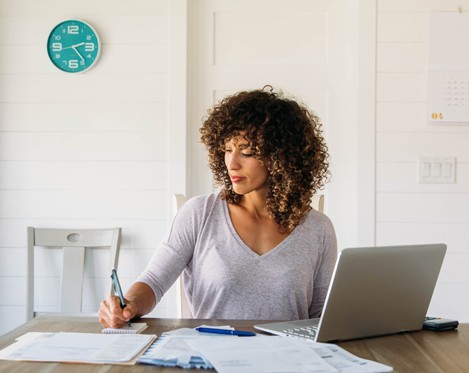 Woman with laptop on desk writing and preparing