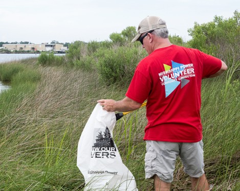 Volunteer picking up trash in a marsh