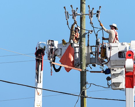 Electric line workers fixing a transmission pole