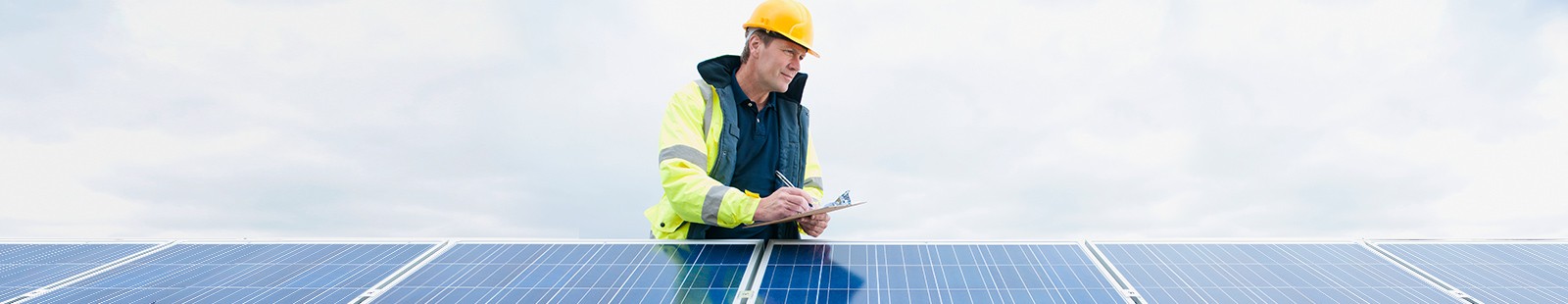 Worker with clipboard checking solar panels