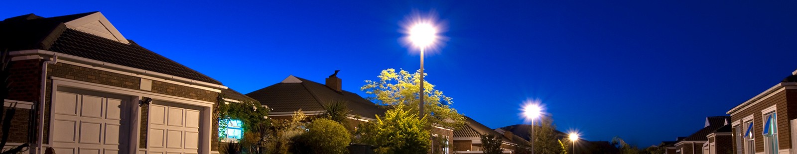 Street view of homes at night with streetlamps