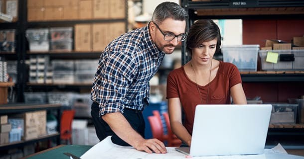 Man and woman looking at a white laptop in their business shop