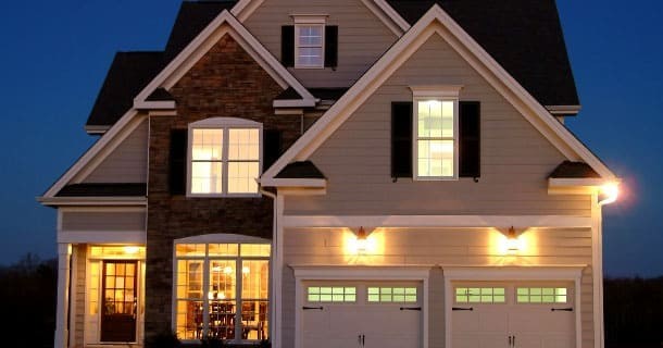 Two story house with garage is lit from the inside after the sun has set