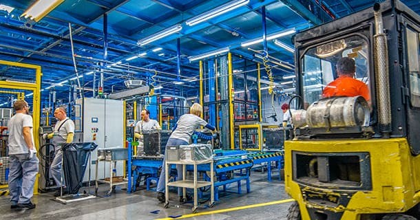 Men and women working in a wearhouse with yellow equipment around them 