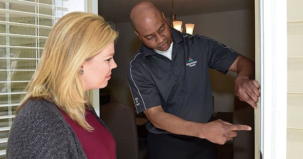 Mississippi Power employee pointing to a fixed doorframe to show a woman what was fixed