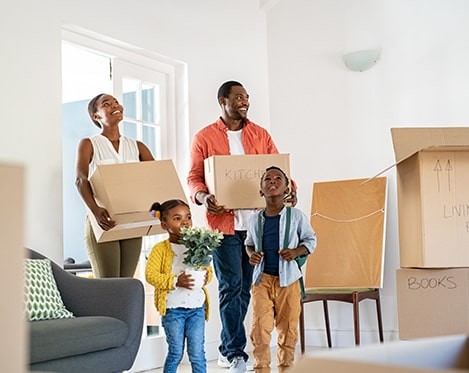 Family holding boxes in new home