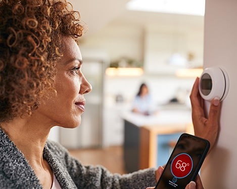 woman adjusting smart thermostat