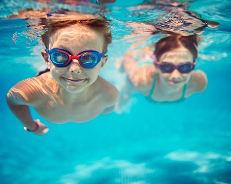kids swimming in pool underwater with goggles on